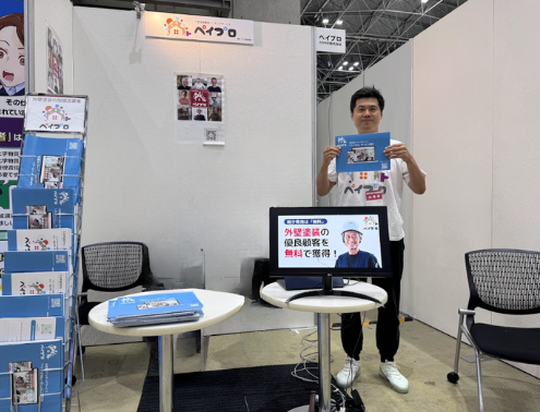 リフォーム産業フェアに出展した際の写真。ブースで代表の松田がチラシを持って立っている。