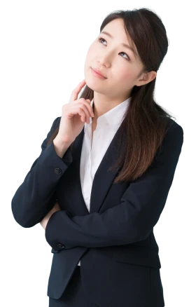 顔に指を当てて困っているスーツ姿の女性の写真。